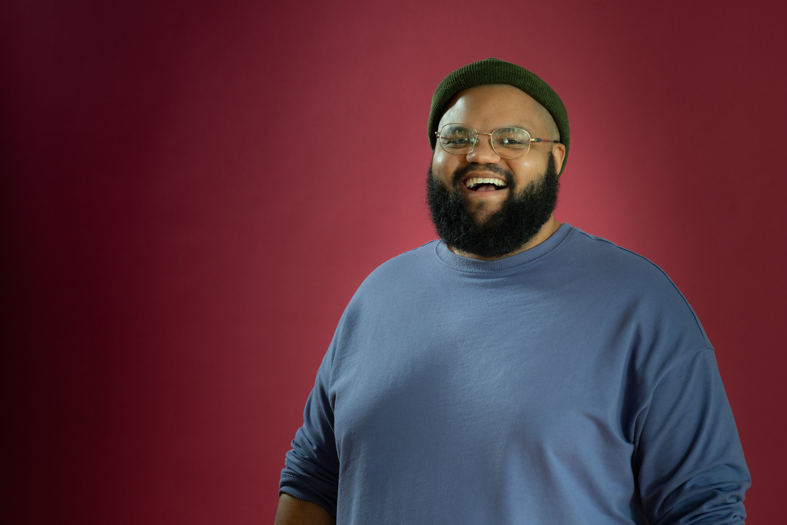 Black man with glasses smiles at the camera.