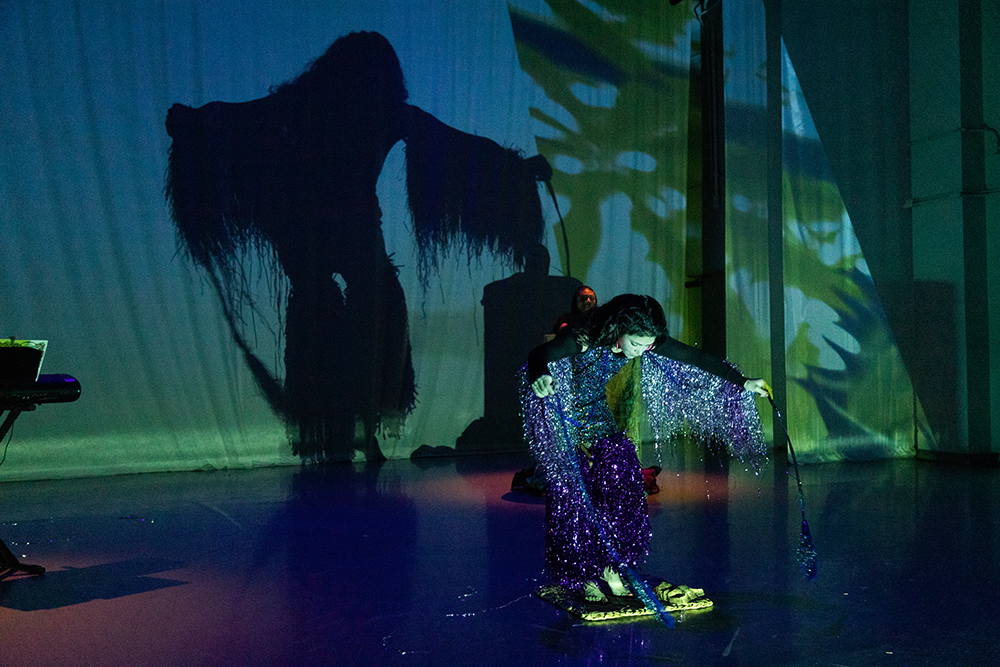 Performer leaning forward with arms out to sides with a shadow casting behind