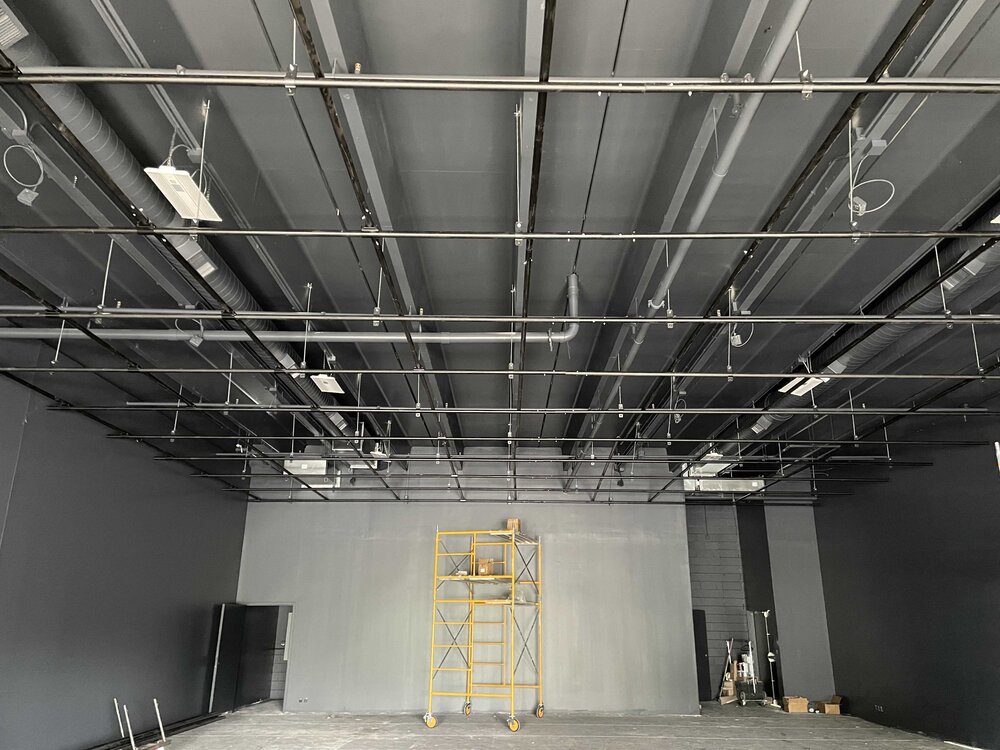 Large room with gray walls lighting grid yellow scaffolding and miscellaneous tools.