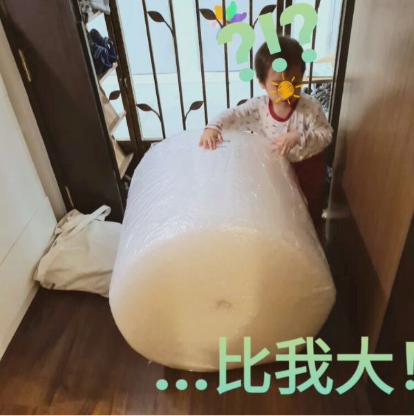 Child holds large roll of plastic sheeting in a doorway, with light green text overlaid.